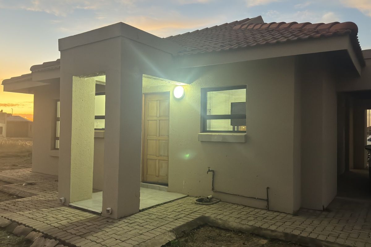 Front elevation of a townhouse featuring a tiled roof, paved entrance walkway, and timber front door at sunset.