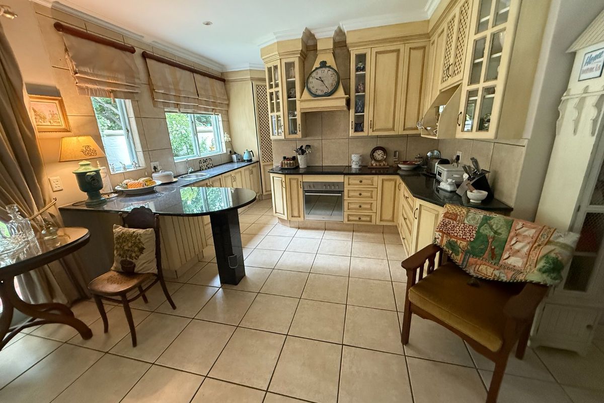 Spacious kitchen featuring traditional timber cabinetry, granite countertops, integrated oven, and a breakfast bar area with tiled flooring throughout.