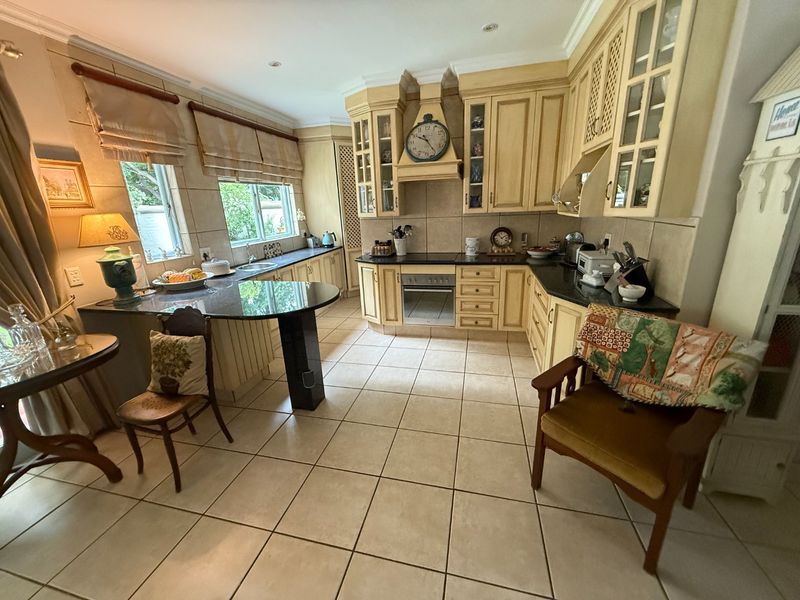 Spacious kitchen featuring traditional timber cabinetry, granite countertops, integrated oven, and a breakfast bar area with tiled flooring throughout.
