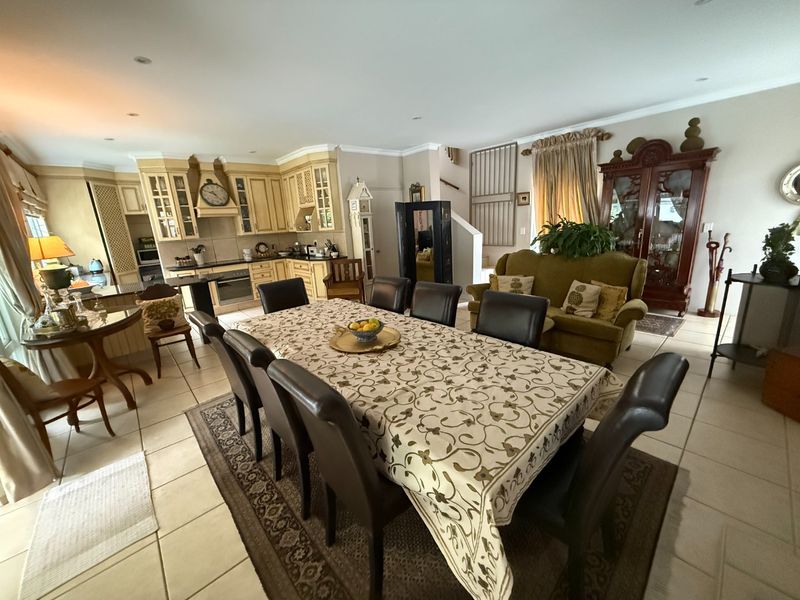Spacious open-plan living and dining area featuring a functional kitchen with built-in cabinetry, oven, and hob, finished with neutral tiled flooring throughout.