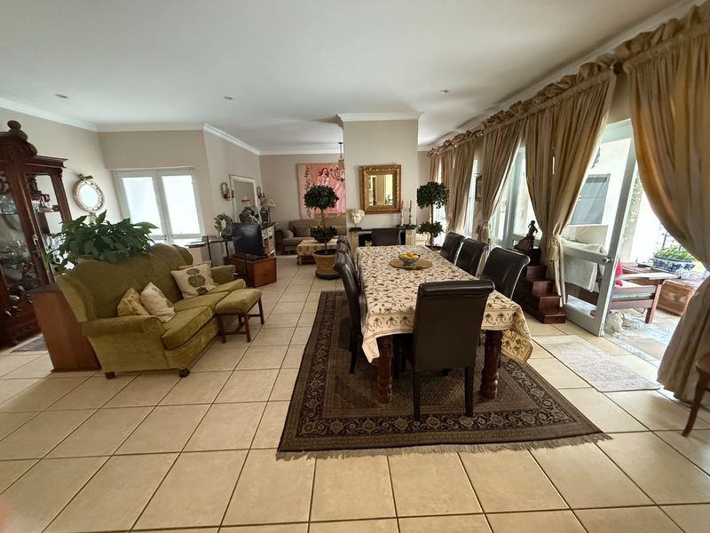 Spacious open-plan living and dining area featuring neutral tiled flooring, recessed lighting, and large sliding glass doors providing access to the outdoor patio.