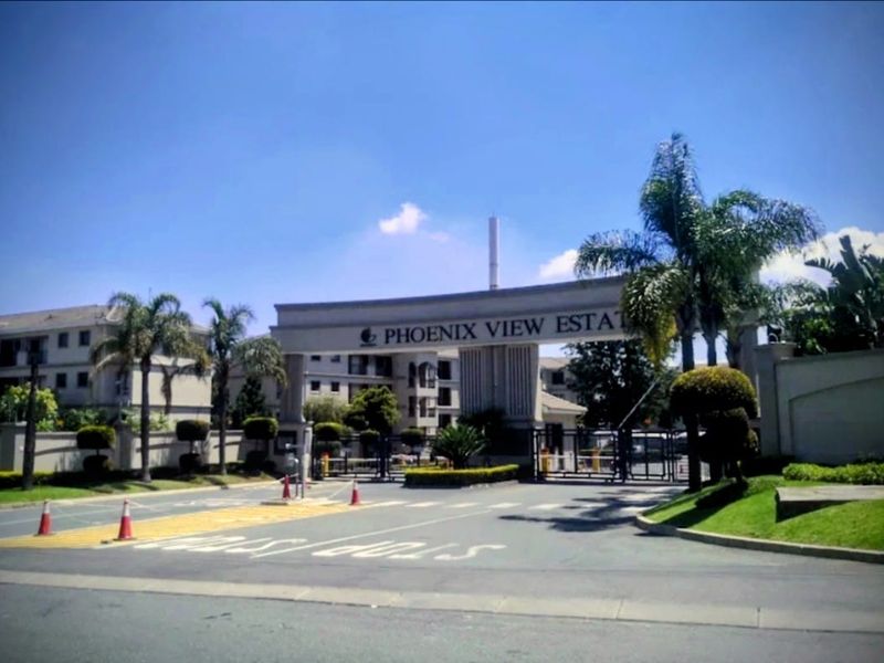 The main entrance gate and security access point for Phoenix View Estate, featuring paved driveway access and established landscaped surroundings.