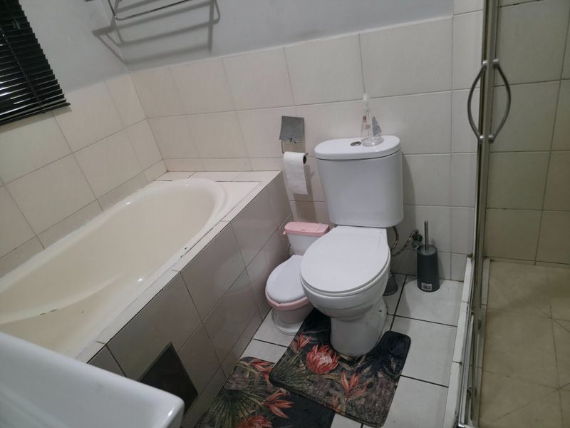 A functional bathroom featuring a built-in bathtub, a separate shower enclosure, and a standard toilet with tiled wall and floor finishes.
