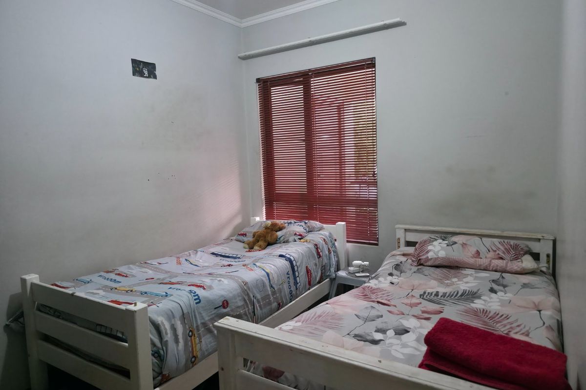 A bedroom featuring red venetian blinds and standard wall finishes, currently configured with two single beds.