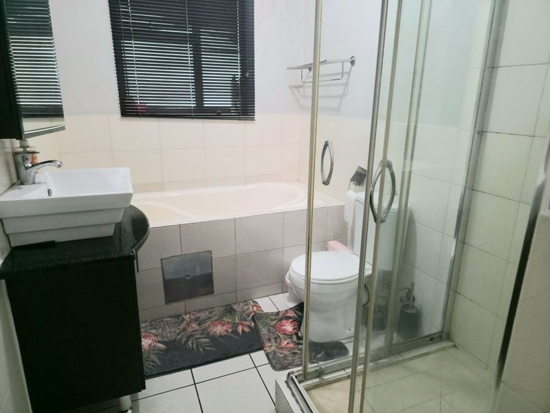 A functional bathroom featuring a vessel sink on a granite vanity, a built-in bathtub, and a separate glass-enclosed shower.