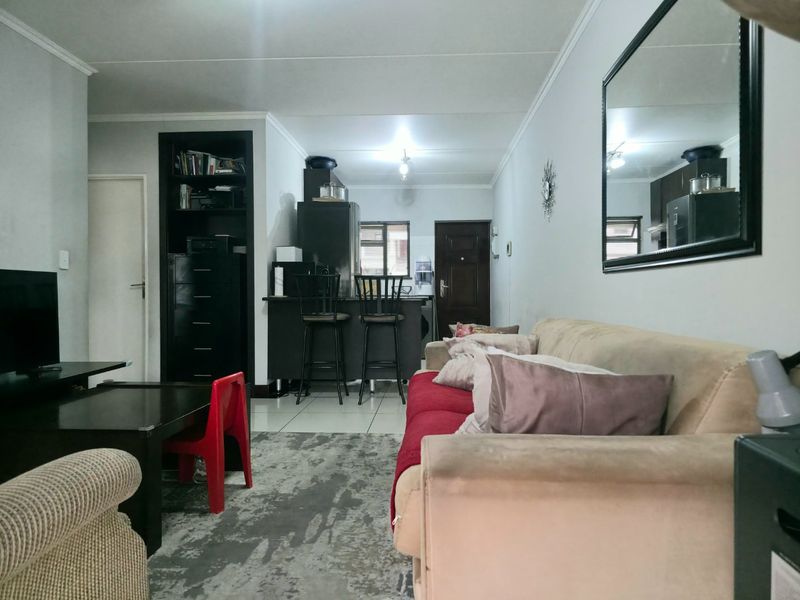 Open plan living area featuring a breakfast bar, built-in shelving, and tiled flooring, creating a functional space for dining and relaxation.