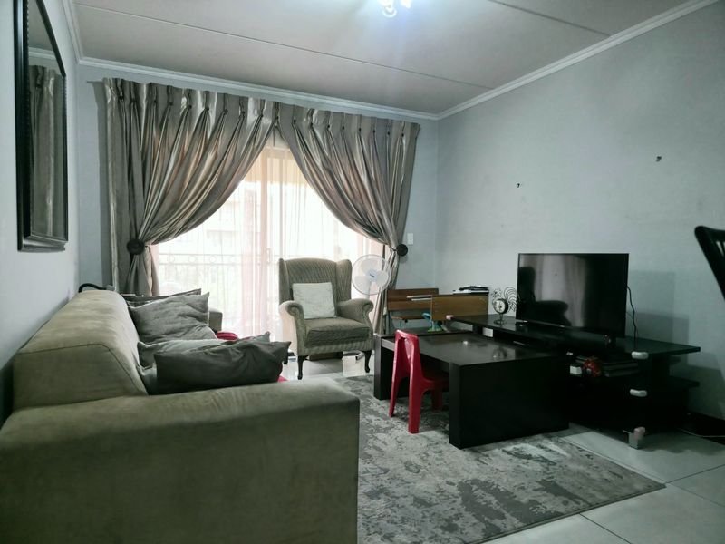 A living room featuring tiled flooring, coved ceilings, and a sliding glass door providing access to a balcony.