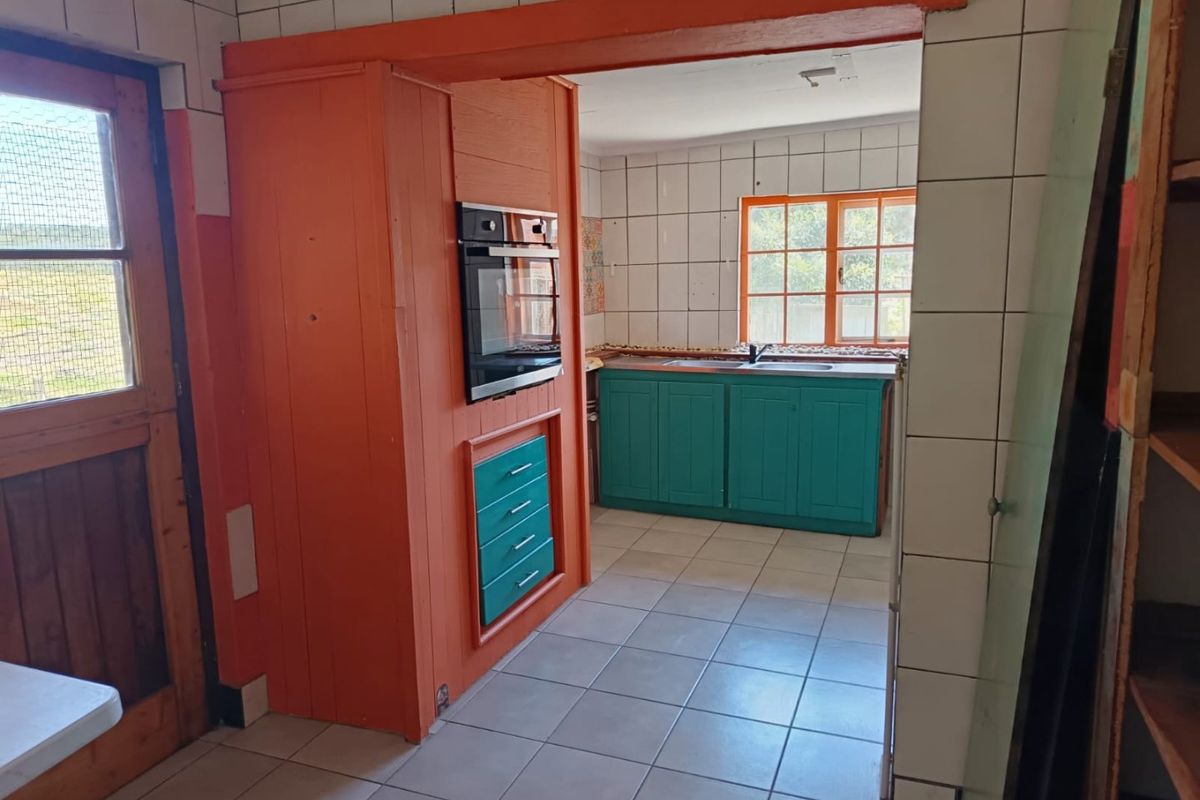A dated kitchen featuring tiled walls and floors, built-in oven, and painted cabinetry, offering a functional layout ready for modernization.