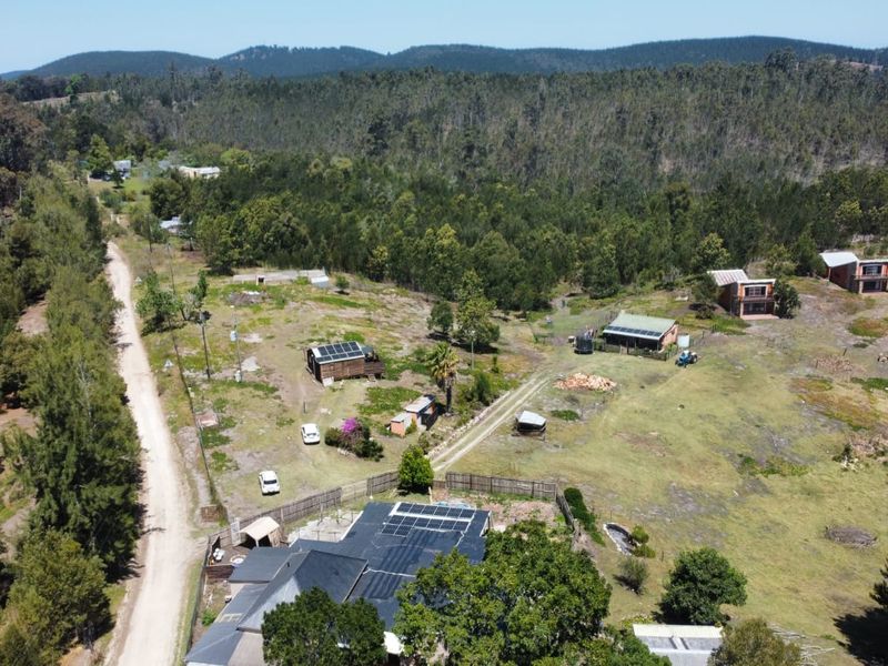 Aerial view of a rural farm property featuring multiple structures, solar panel installations, and expansive surrounding landscape.