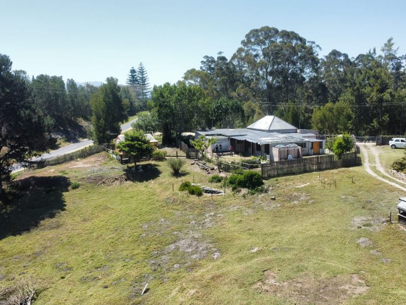 Aerial view of a rural farm property featuring a main dwelling with a metal roof, surrounding timber fencing, and expansive open land.