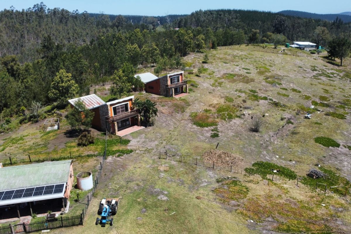 Aerial view of a farm property featuring multiple residential structures, solar panels, and expansive surrounding landscape.