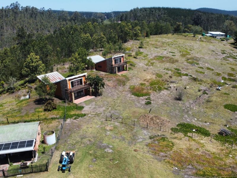 Aerial view of a farm property featuring multiple residential structures, solar panels, and expansive surrounding landscape.