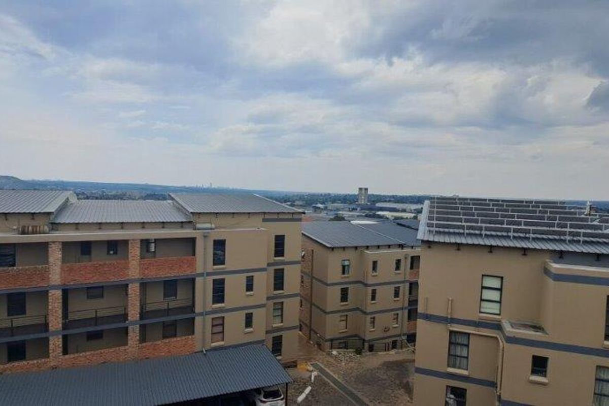 An elevated aerial view of the apartment complex, showcasing the building architecture, metal roofing, and installed solar panel arrays.