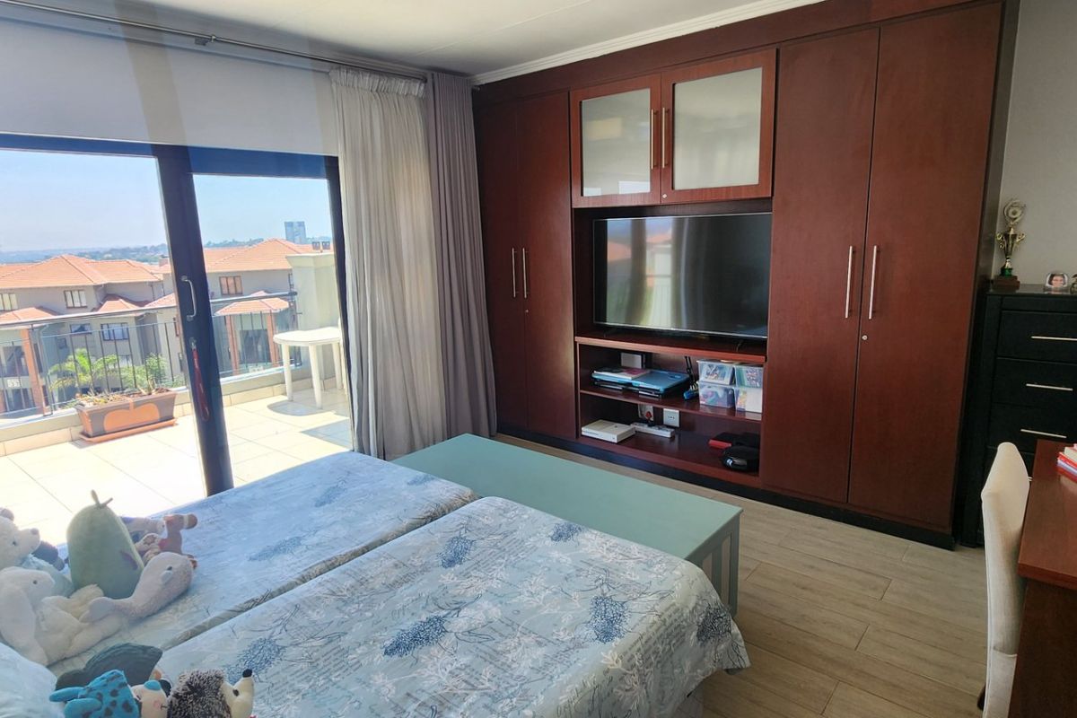 Spacious bedroom featuring extensive built-in cabinetry, laminate flooring, and a large sliding glass door providing access to a private balcony.