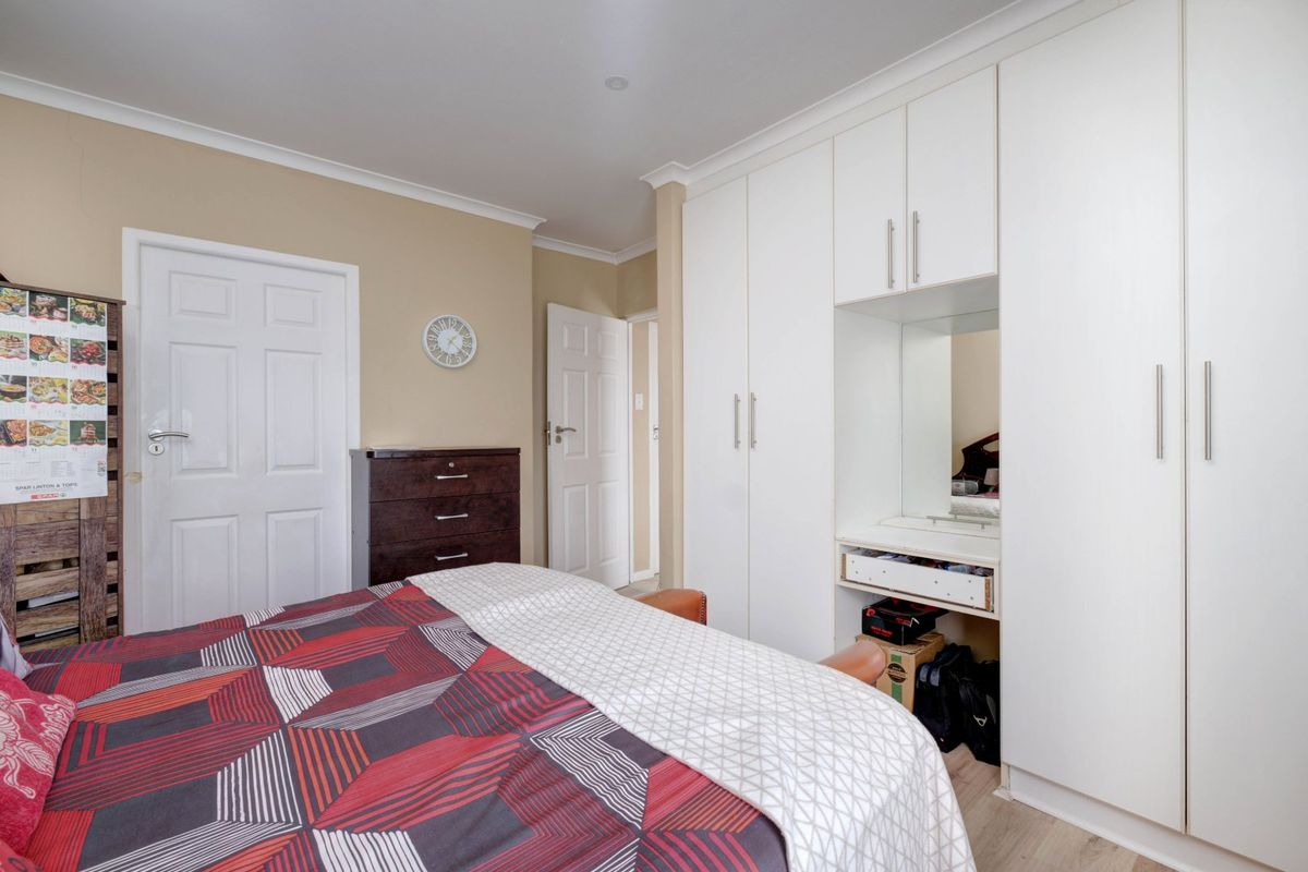 A bedroom featuring built-in white cabinetry with an integrated vanity mirror and storage space.