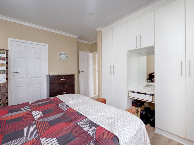 A bedroom featuring built-in white cabinetry with an integrated vanity mirror and storage space.