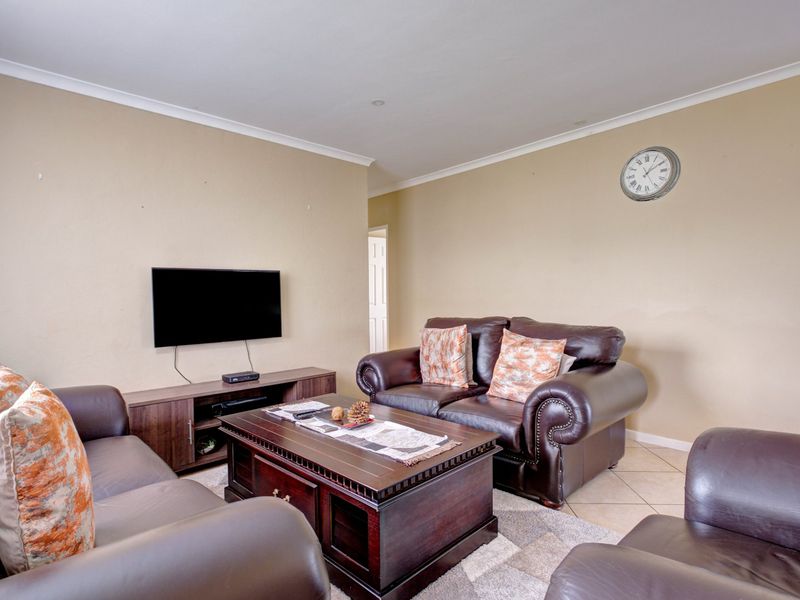 A comfortable living room featuring tiled flooring, recessed downlighting, and neutral wall finishes, providing a functional and inviting space for relaxation.
