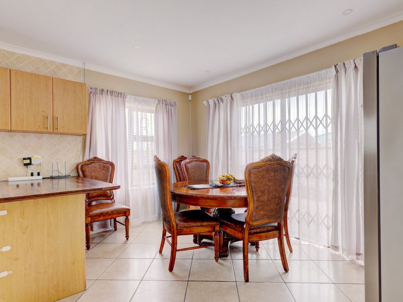 Open plan dining area featuring tiled flooring, built-in cabinetry, and large windows with security gates, providing access to the outdoor space.