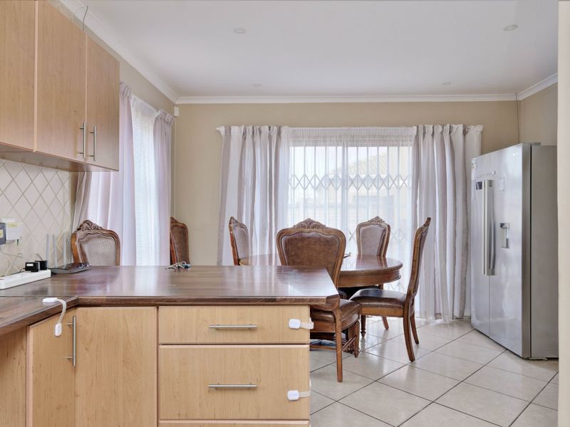 Open-plan kitchen and dining area featuring light wood-finish cabinetry, laminate countertops, tiled flooring, and direct access to the exterior via a sliding glass door.