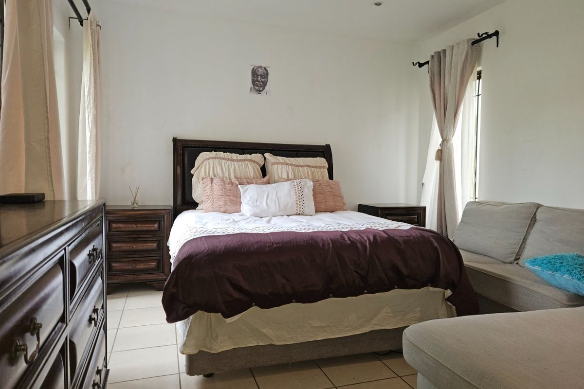 A bedroom featuring tiled flooring and dual window treatments, providing a functional space with neutral wall finishes.