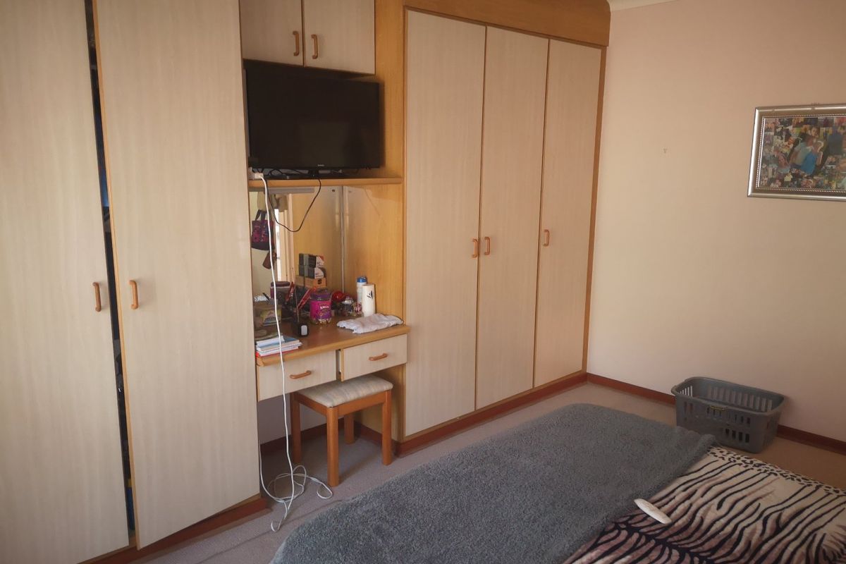 A bedroom featuring extensive built-in cabinetry, including a vanity unit and floor-to-ceiling wardrobes with light wood-grain finish.
