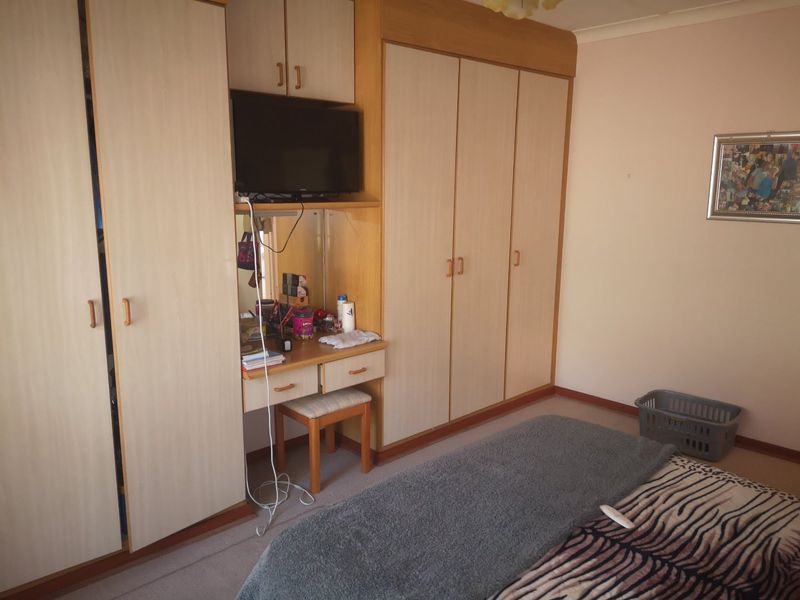 A bedroom featuring extensive built-in cabinetry, including a vanity unit and floor-to-ceiling wardrobes with light wood-grain finish.