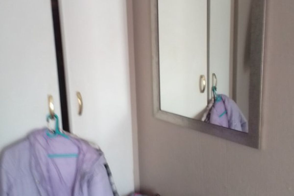 A bedroom corner featuring a white built-in wardrobe and a wall-mounted mirror.