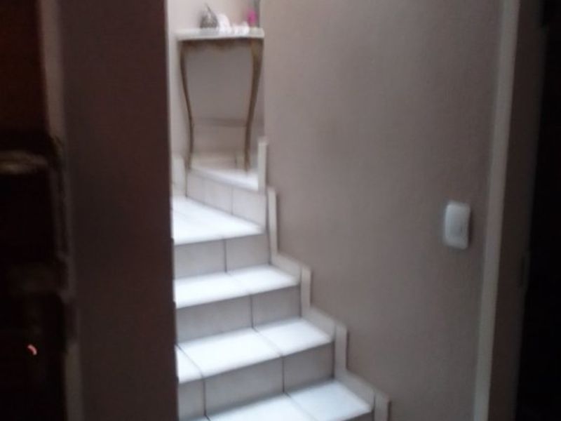 A narrow interior hallway featuring a tiled staircase leading to an upper level.