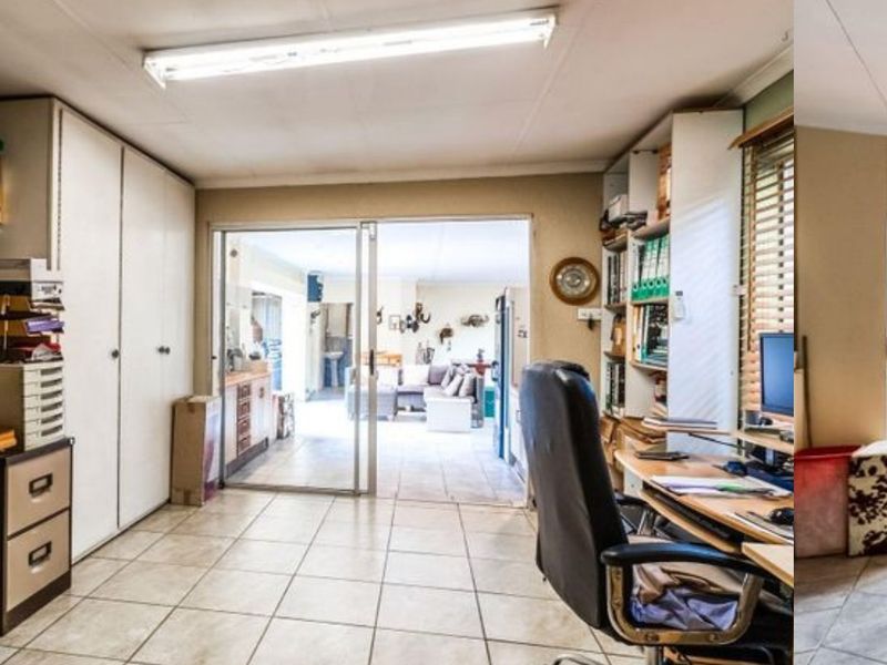 A functional home office space featuring built-in cabinetry, tiled flooring, and sliding glass doors providing a view into the adjacent living area.