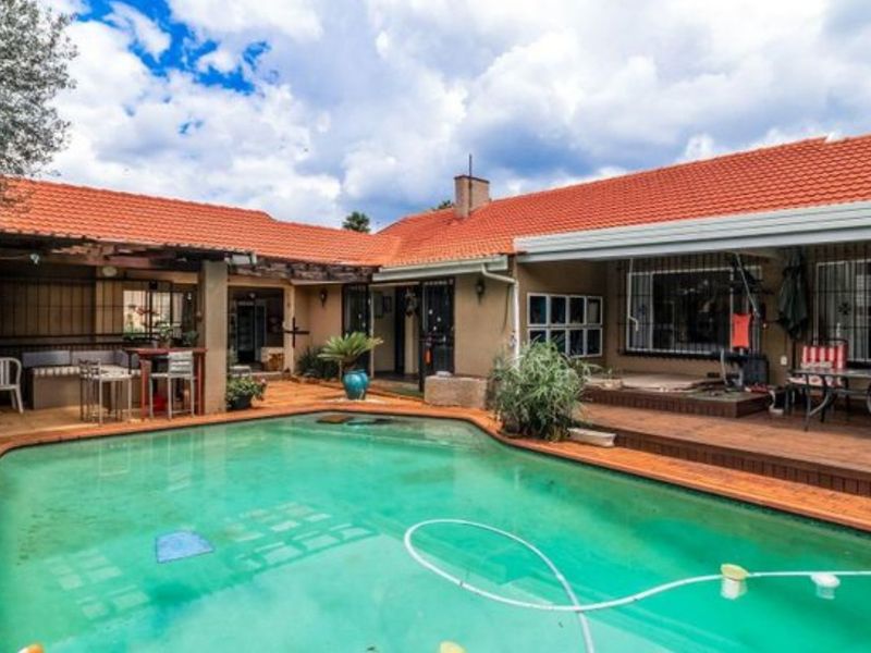 Spacious rear courtyard featuring a swimming pool, covered patio area, and timber decking, ideal for outdoor entertaining.