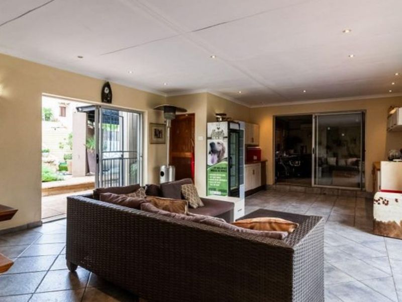 Spacious open-plan living area featuring tiled flooring, recessed ceiling lighting, and large sliding glass doors providing seamless access to the outdoor patio.