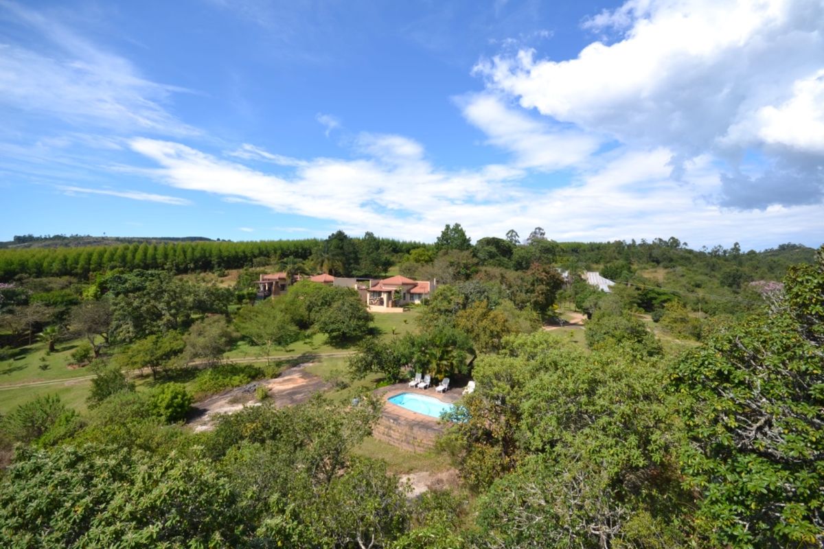 An aerial view of a farm property featuring a swimming pool, mature trees, and residential buildings set within a spacious rural landscape.