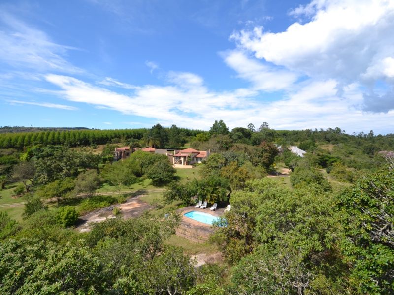 An aerial view of a farm property featuring a swimming pool, mature trees, and residential buildings set within a spacious rural landscape.