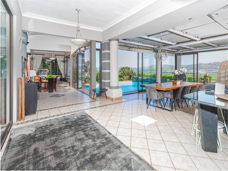 Spacious open-plan living and dining area featuring large sliding glass doors that open to a swimming pool and scenic landscape views.