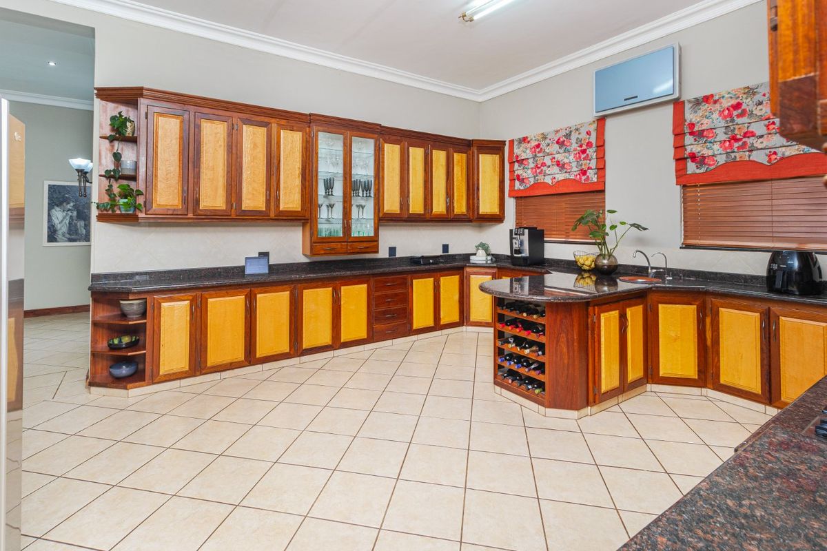 Spacious kitchen featuring extensive wooden cabinetry, granite countertops, a built-in wine rack, and ceramic tiled flooring.