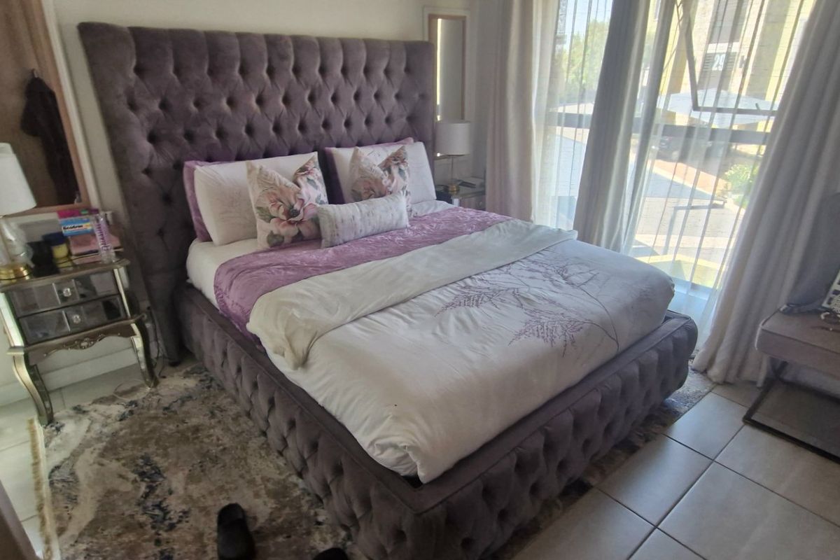 A well-lit bedroom featuring tiled flooring and a large sliding glass door providing natural light and access to the exterior.