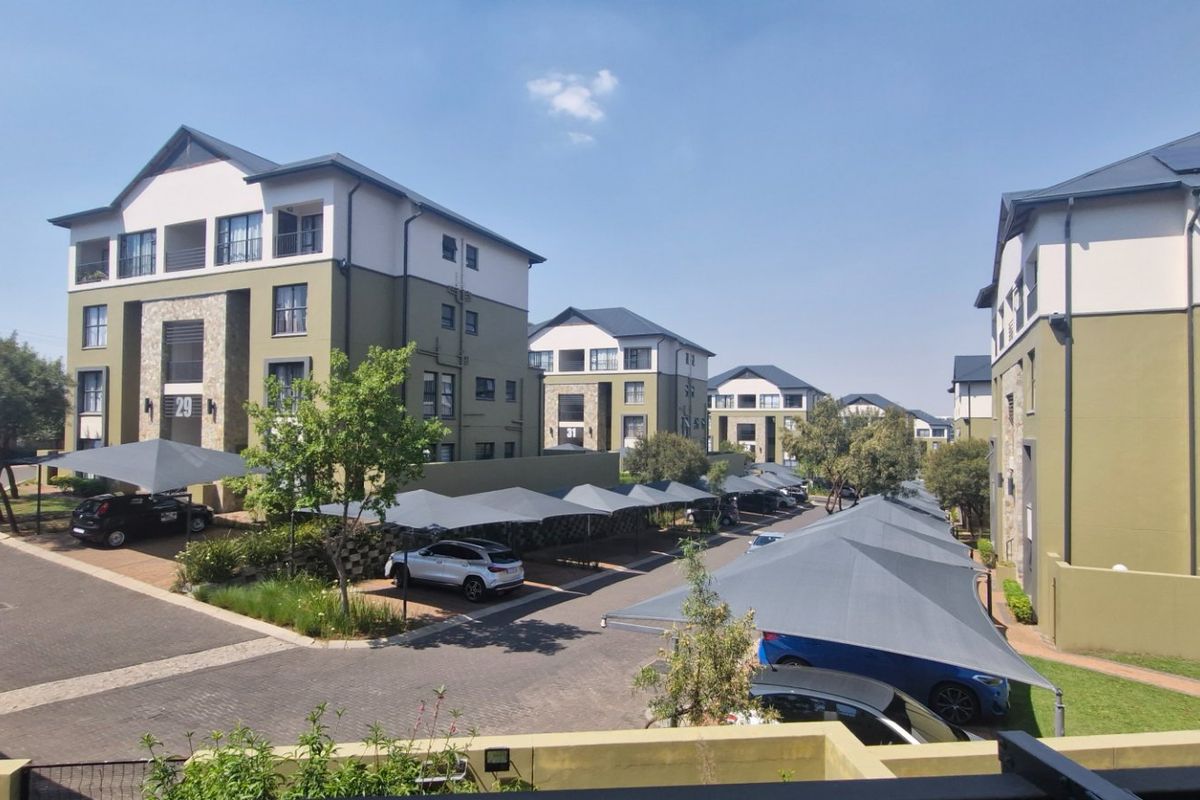 An elevated view of a townhouse complex featuring multi-story residential buildings, paved driveways, and covered parking bays.