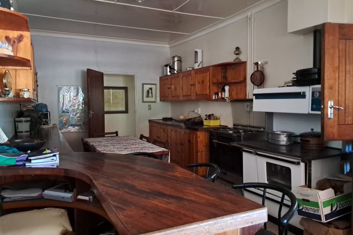A rustic farm-style kitchen featuring wooden cabinetry, a built-in oven, and a large breakfast bar, offering a functional layout with potential for modernization.