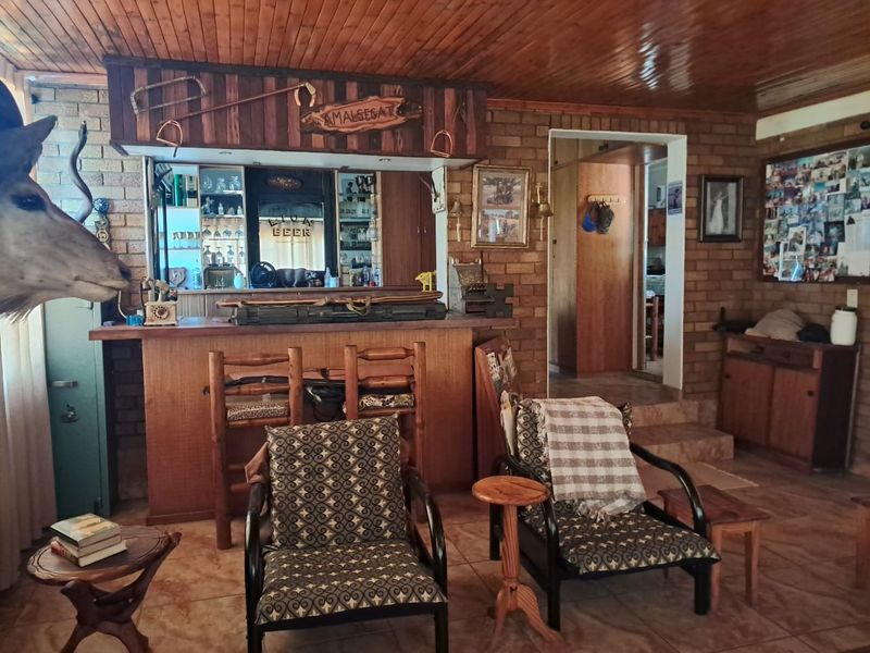 A rustic-style home bar area featuring exposed brick walls, a timber-clad ceiling, and a built-in bar counter with integrated shelving.