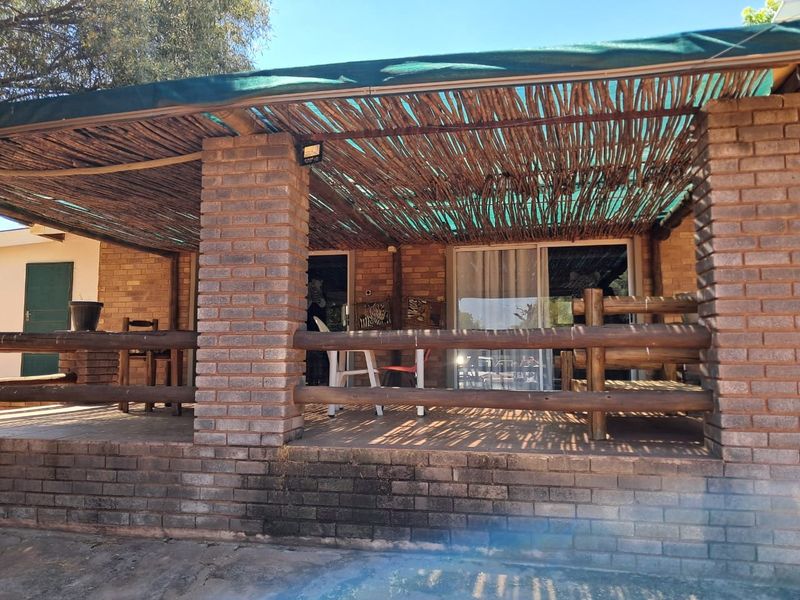 Covered outdoor patio featuring brick pillars, a rustic thatched roof, and sliding glass door access to the main dwelling.