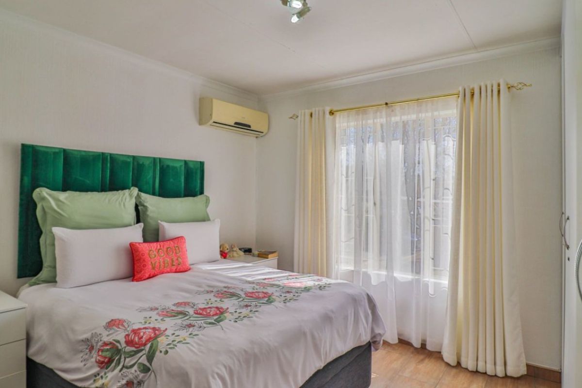 A well-maintained bedroom featuring laminate flooring, a built-in wardrobe, and a wall-mounted air conditioning unit.