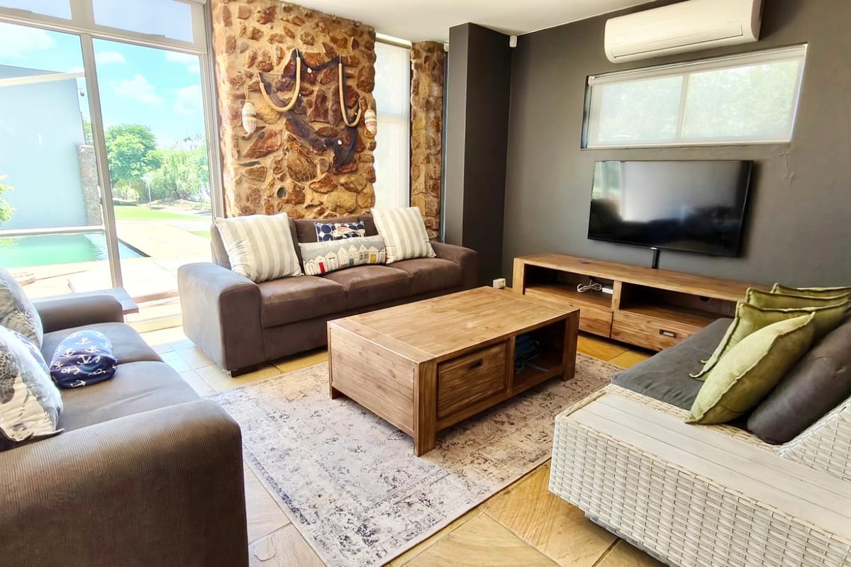 A comfortable living room featuring a natural stone feature wall, large sliding glass doors, and a wall-mounted air conditioning unit.