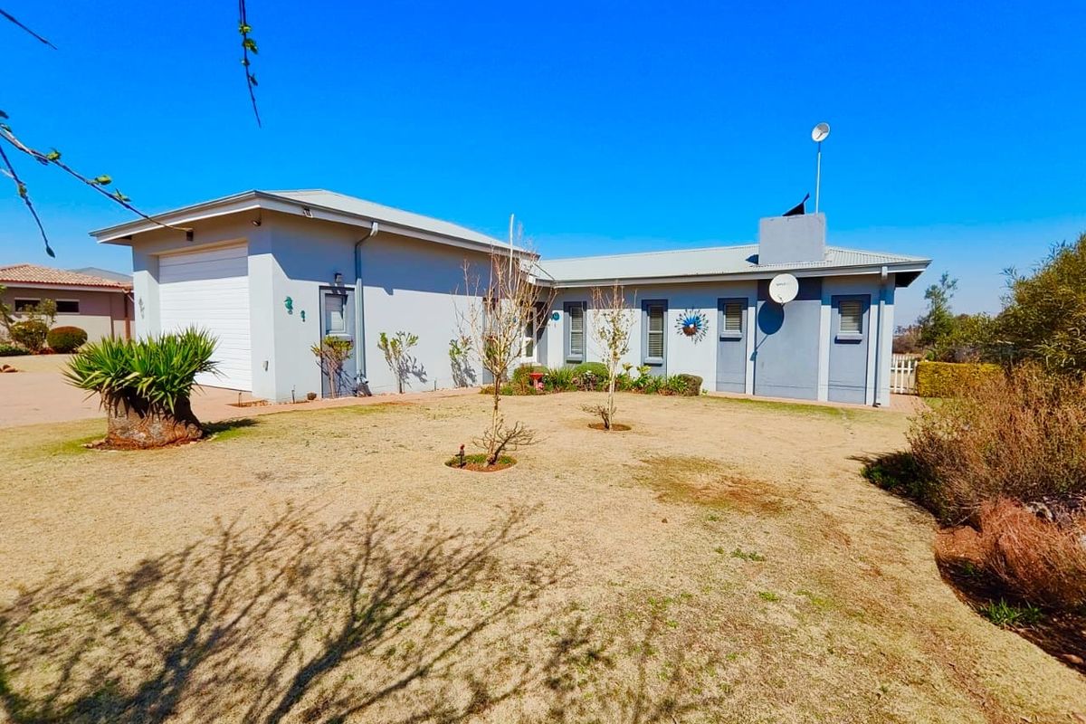 A view of the rear exterior of the house, featuring a single-car garage, paved driveway, and a spacious garden area.