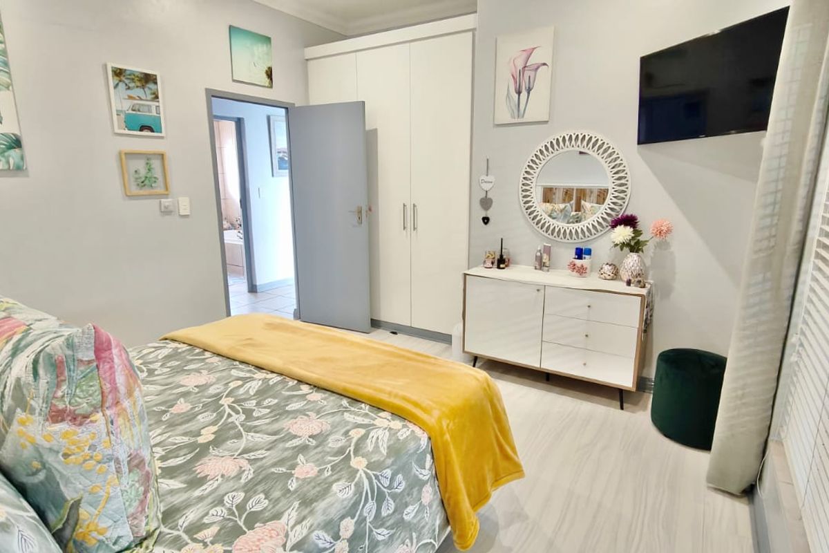 A well-maintained bedroom featuring built-in wardrobes, light-toned flooring, and direct access to an adjoining bathroom.