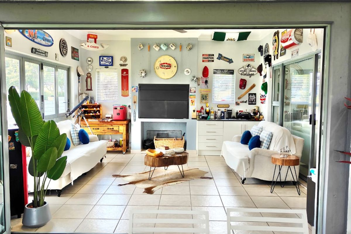 A spacious living area featuring large folding glass doors, tiled flooring, and a central fireplace, creating a seamless transition to outdoor spaces.