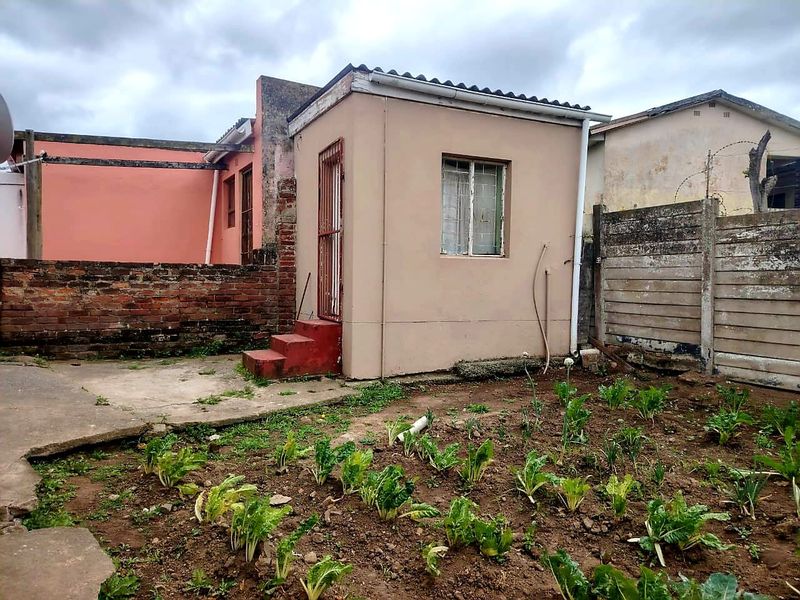 Rear exterior view of the property featuring a small concrete patio, garden area, and boundary walls.