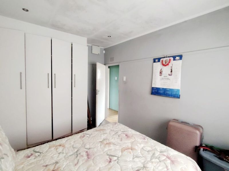 A bedroom featuring built-in cupboards and recessed lighting, currently showing signs of ceiling water damage and wear.