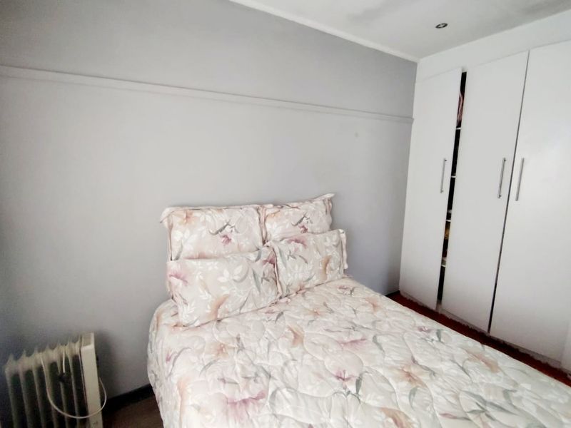 A bedroom featuring built-in white cupboards and recessed ceiling lighting, providing functional storage and neutral finishes.