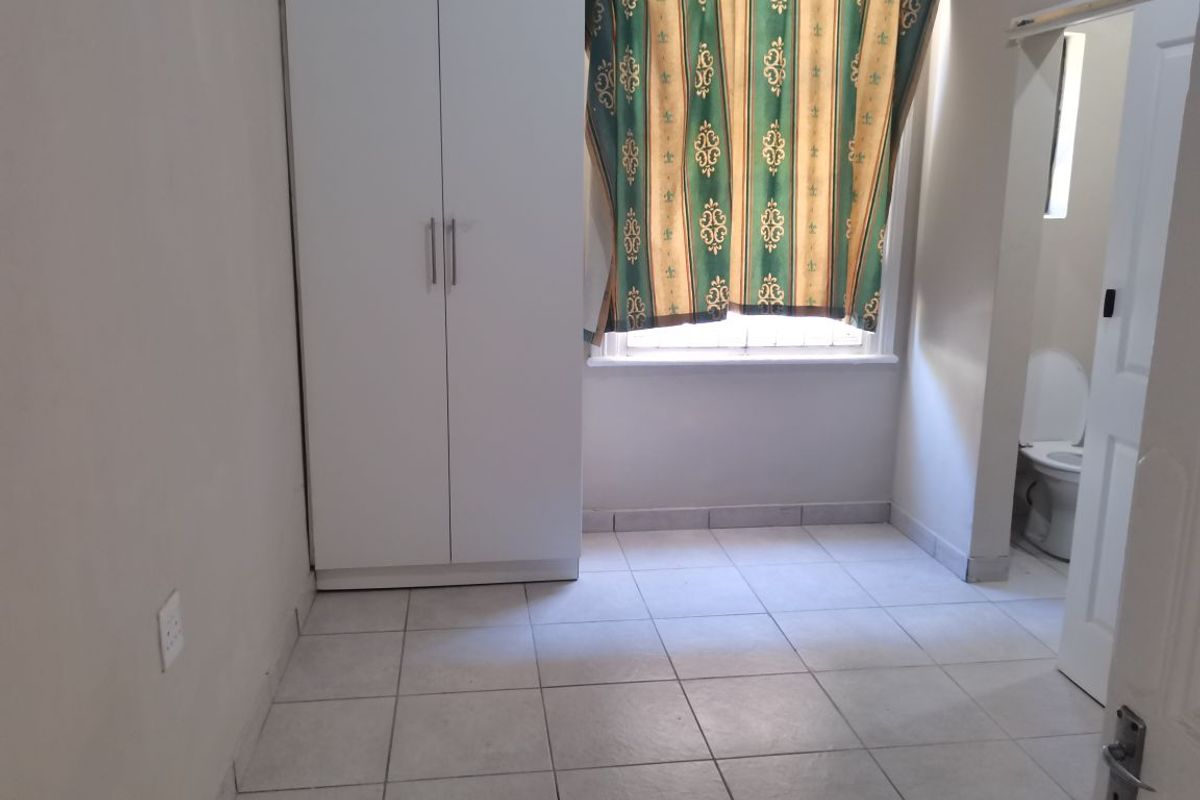 A bedroom featuring tiled flooring, a built-in wardrobe, and an en-suite bathroom access point.