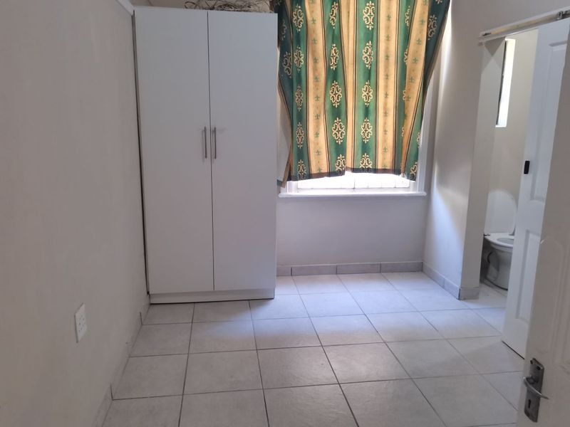 A bedroom featuring tiled flooring, a built-in wardrobe, and an en-suite bathroom access point.